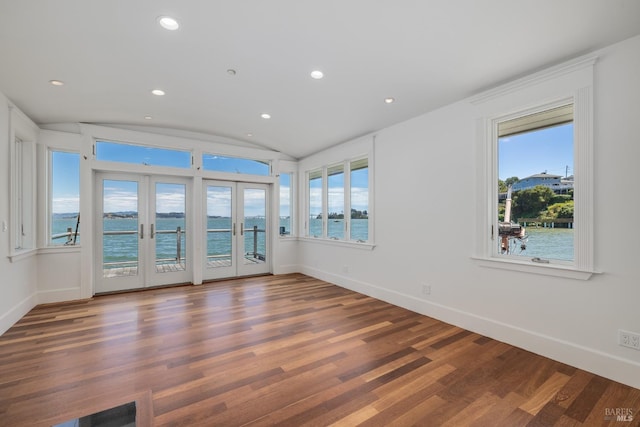 unfurnished room featuring hardwood / wood-style flooring, a water view, french doors, and vaulted ceiling