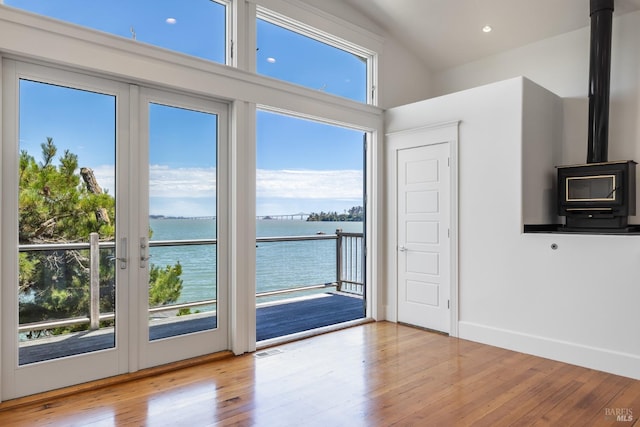 entryway featuring french doors, a water view, a wood stove, and light hardwood / wood-style flooring