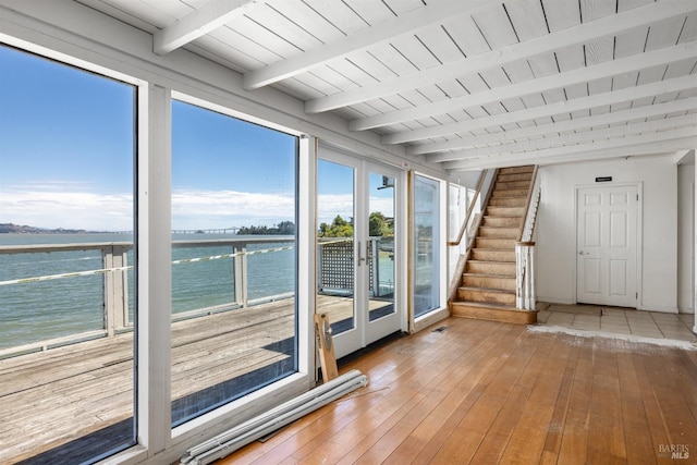 doorway to outside featuring beamed ceiling, a water view, a healthy amount of sunlight, and hardwood / wood-style flooring