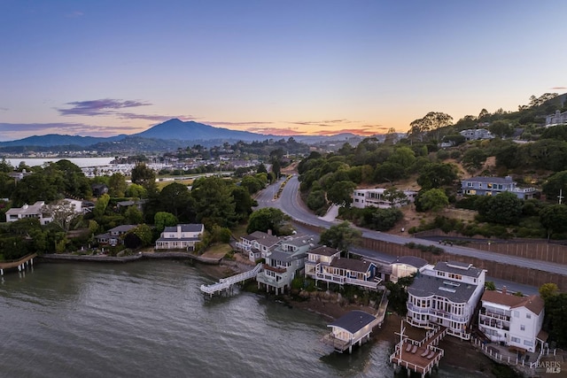 aerial view at dusk featuring a water and mountain view