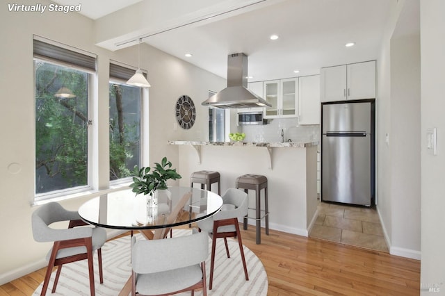 dining space featuring baseboards, light wood finished floors, and recessed lighting