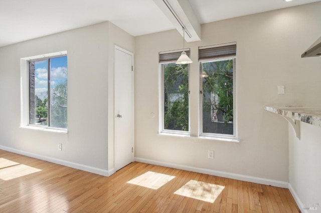 interior space featuring beamed ceiling, baseboards, and hardwood / wood-style flooring