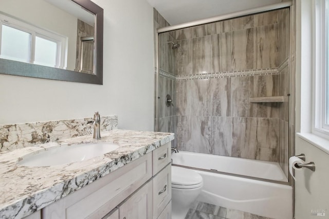 full bathroom with plenty of natural light, toilet, vanity, and tiled shower / bath