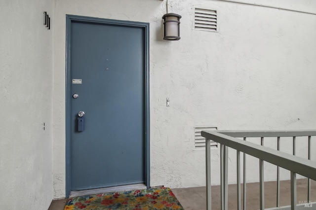 property entrance with stucco siding and visible vents