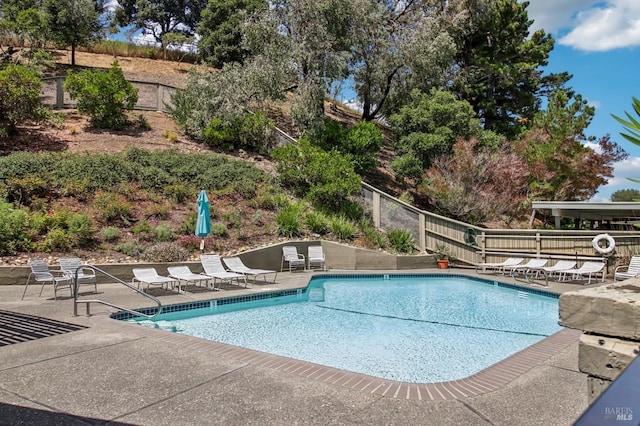 pool with a patio area and fence
