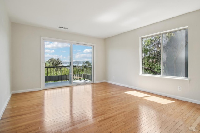 empty room featuring visible vents, baseboards, and light wood-style floors