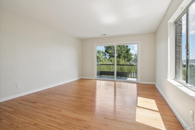 unfurnished room featuring light wood finished floors, visible vents, and baseboards