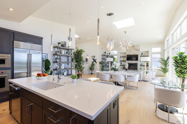 kitchen featuring sink, built in fridge, light hardwood / wood-style flooring, and light stone counters