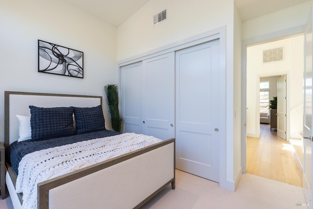 bedroom featuring light hardwood / wood-style flooring, a closet, and vaulted ceiling