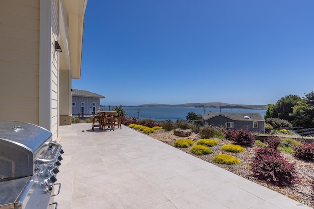 view of patio / terrace featuring grilling area and a water view