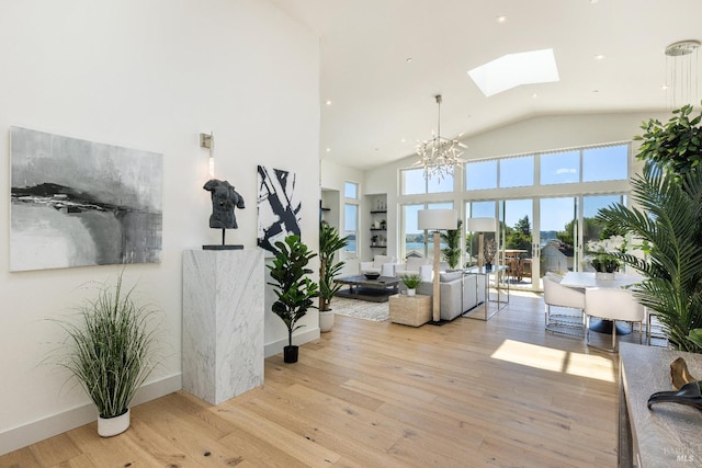 living room featuring a skylight, light hardwood / wood-style flooring, high vaulted ceiling, and a chandelier