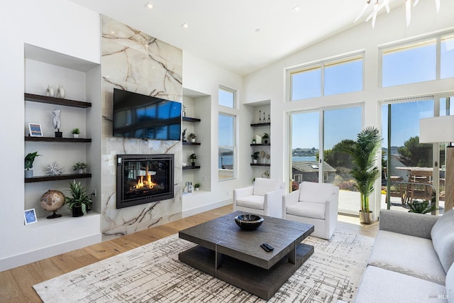 living room with light hardwood / wood-style floors, a fireplace, a healthy amount of sunlight, and built in features