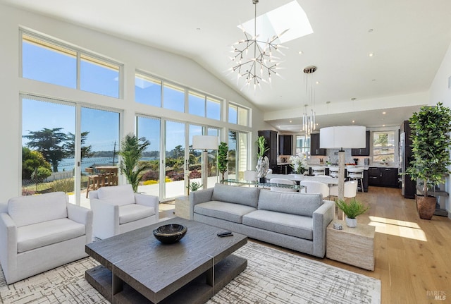 living room with light hardwood / wood-style floors, vaulted ceiling, and an inviting chandelier