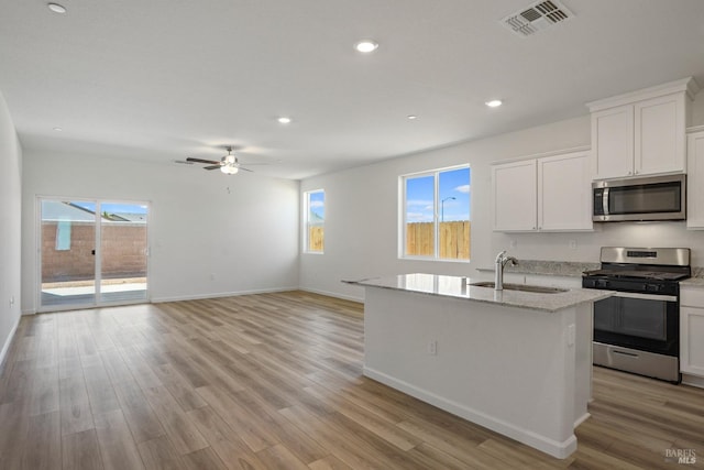 kitchen with light wood-type flooring, an island with sink, white cabinets, and appliances with stainless steel finishes