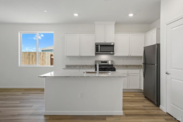 kitchen with light stone countertops, appliances with stainless steel finishes, and white cabinets