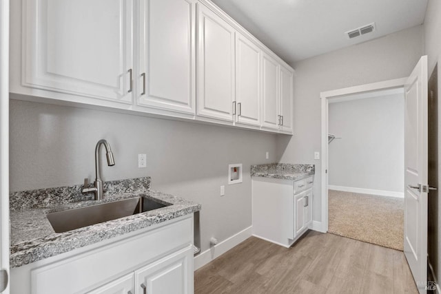 clothes washing area with cabinets, hookup for a washing machine, light hardwood / wood-style flooring, and sink