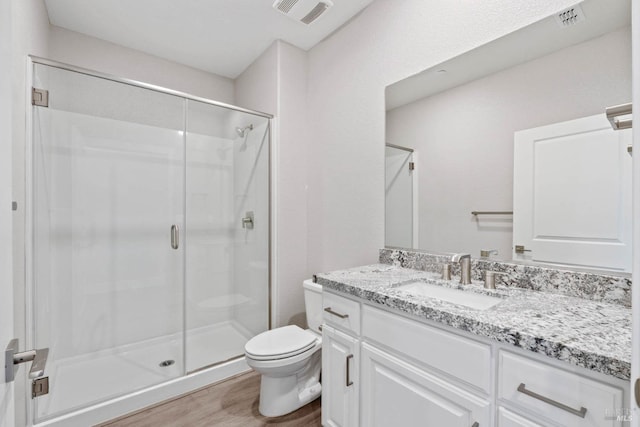 bathroom with hardwood / wood-style floors, vanity, an enclosed shower, and toilet