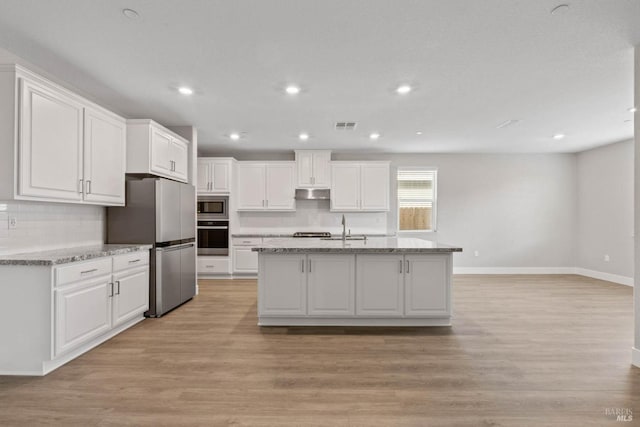 kitchen with white cabinets, stainless steel appliances, light hardwood / wood-style flooring, and light stone counters