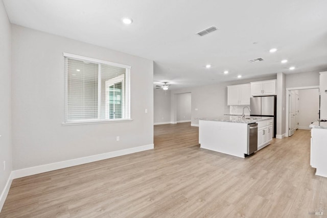 kitchen featuring white cabinets, ceiling fan, stainless steel fridge, light hardwood / wood-style floors, and light stone counters