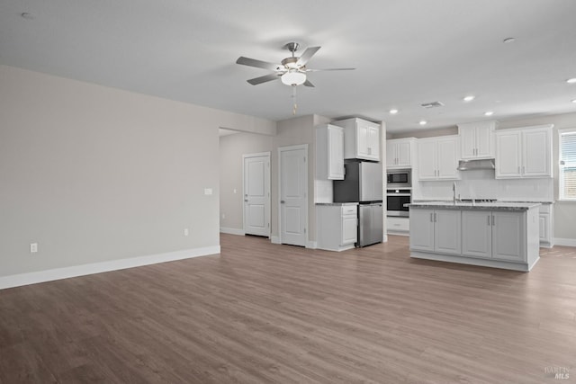 kitchen with ceiling fan, stainless steel appliances, an island with sink, white cabinets, and light wood-type flooring