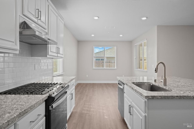 kitchen with white cabinetry, appliances with stainless steel finishes, sink, and a kitchen island with sink