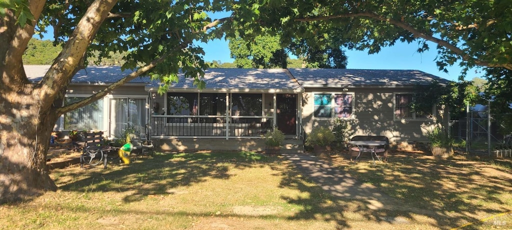 back of property with a yard and a sunroom