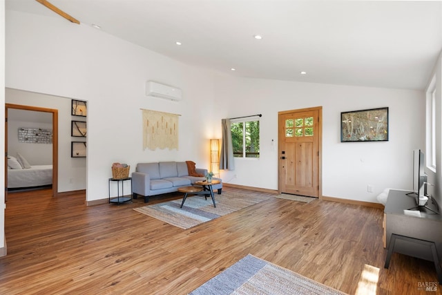 living room featuring hardwood / wood-style flooring, a wall mounted air conditioner, and high vaulted ceiling