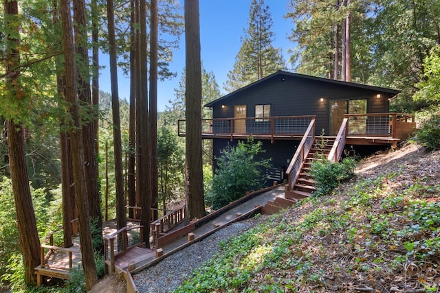 rear view of house featuring stairs and a deck