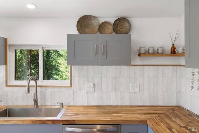 kitchen featuring sink, gray cabinets, wooden counters, tasteful backsplash, and stainless steel dishwasher