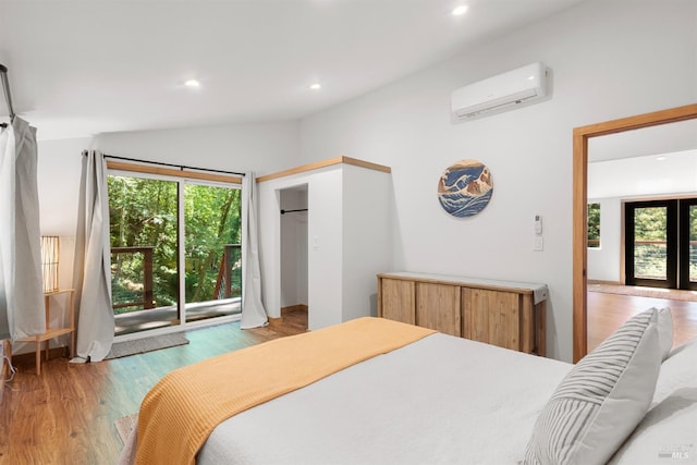 bedroom with french doors, a wall mounted air conditioner, vaulted ceiling, light wood-type flooring, and access to outside