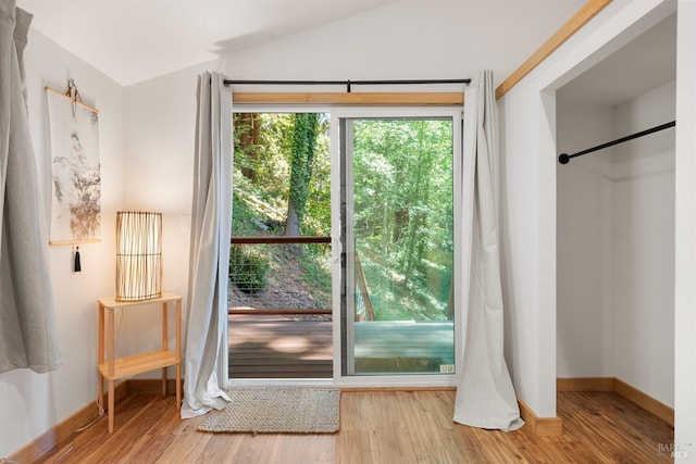 doorway featuring lofted ceiling and light wood-type flooring