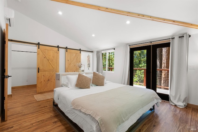 bedroom featuring lofted ceiling, hardwood / wood-style floors, an AC wall unit, and a barn door