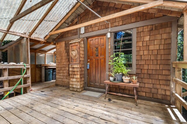 carpeted living room featuring wood ceiling, wooden walls, lofted ceiling with beams, and a wood stove