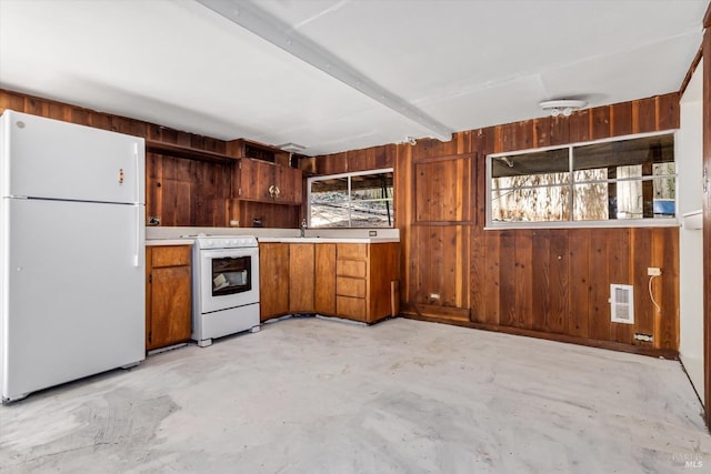 kitchen featuring beamed ceiling, wooden walls, sink, and white appliances