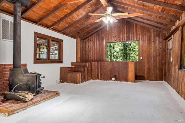 bonus room with concrete flooring, vaulted ceiling with beams, wood ceiling, a wood stove, and wooden walls