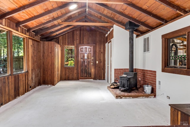 interior space featuring a healthy amount of sunlight, a wood stove, vaulted ceiling with beams, and wood ceiling