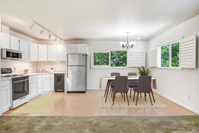 kitchen with appliances with stainless steel finishes, white cabinetry, a wealth of natural light, and light wood-type flooring