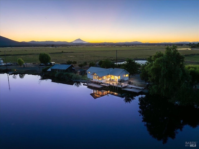 aerial view at dusk featuring a water and mountain view and a rural view