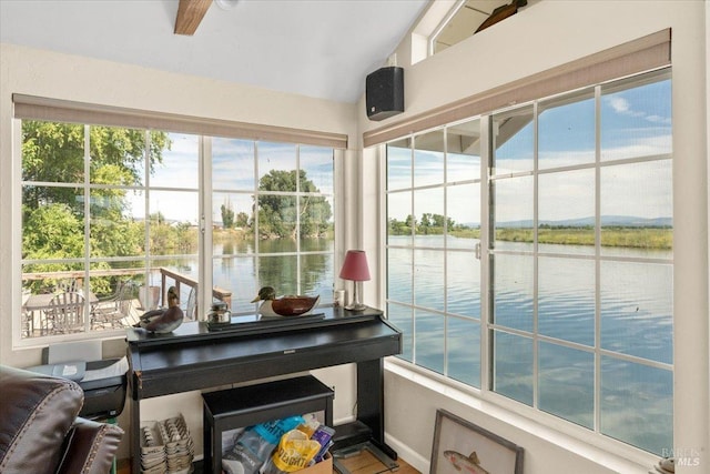 sunroom featuring a water view and lofted ceiling