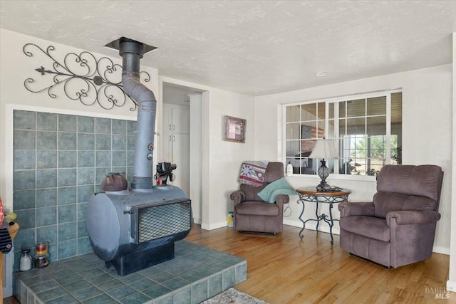 living room featuring a textured ceiling, tile walls, hardwood / wood-style flooring, and a wood stove