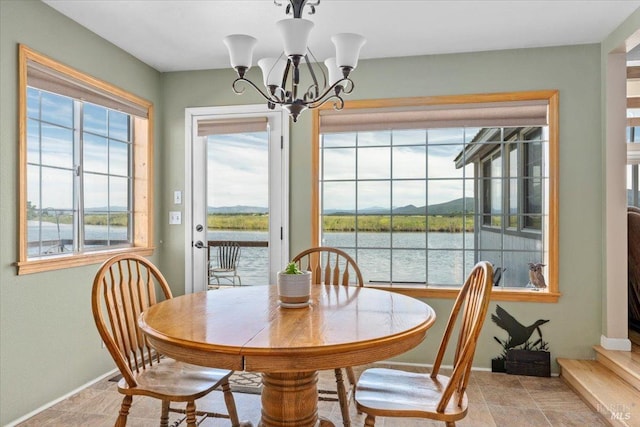 dining space with a notable chandelier, a water view, and tile patterned flooring