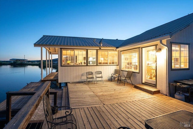 deck at dusk with a water view and a dock