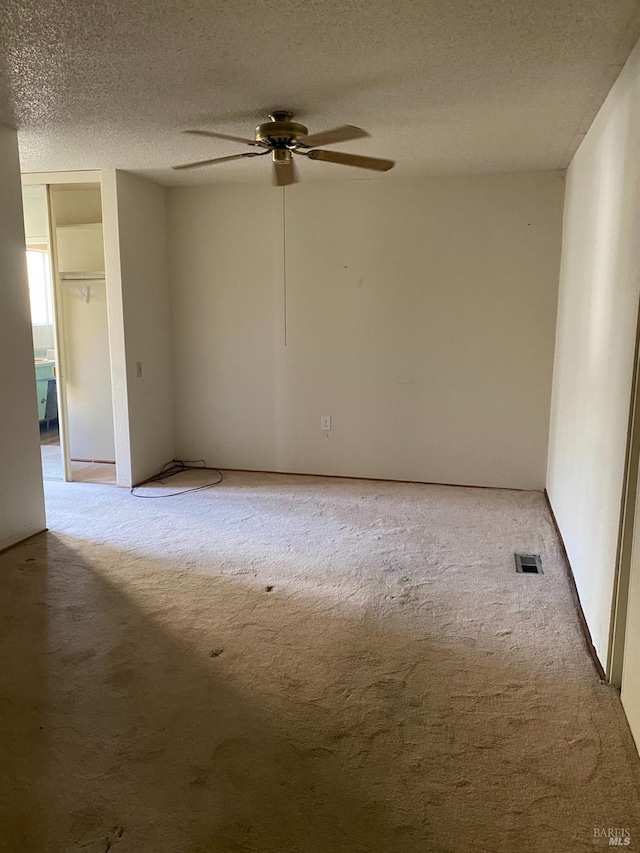 spare room featuring carpet flooring, ceiling fan, and a textured ceiling