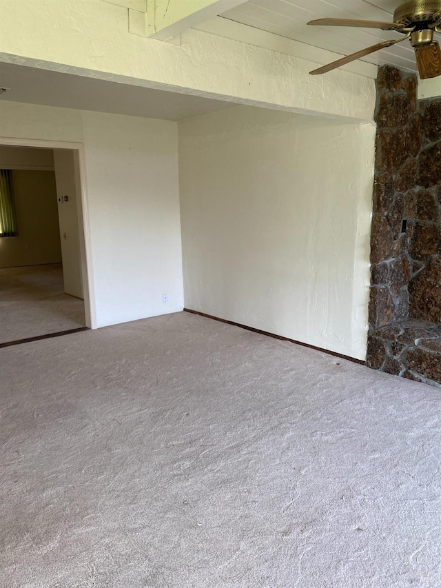 spare room with ceiling fan, beam ceiling, and carpet floors