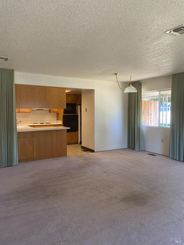 kitchen with black appliances, decorative light fixtures, kitchen peninsula, and light carpet