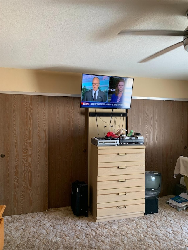 bedroom with ceiling fan, wooden walls, a textured ceiling, and carpet floors