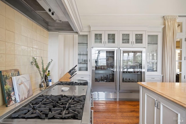 kitchen with white cabinets, dark wood-type flooring, ornamental molding, and backsplash