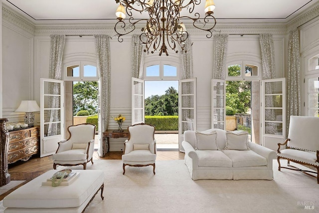 living room with hardwood / wood-style floors, plenty of natural light, an inviting chandelier, and crown molding