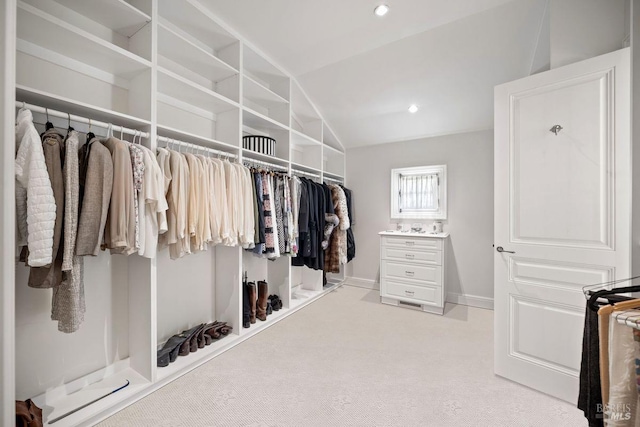 walk in closet with vaulted ceiling and light colored carpet