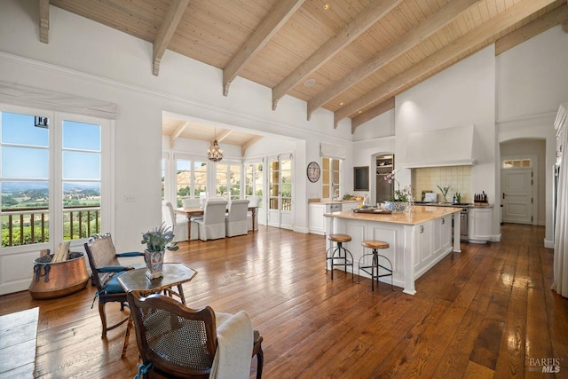 kitchen with hardwood / wood-style floors, white cabinetry, high vaulted ceiling, backsplash, and a kitchen island